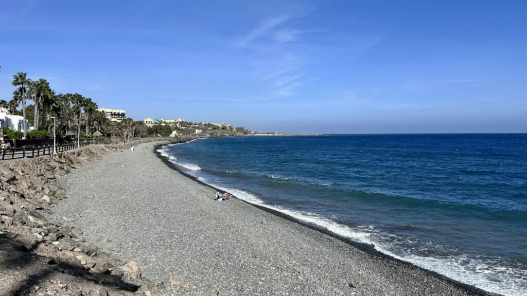 The pebble beach in Bahía Feliz with a promenade and palm trees, southern Gran Canaria