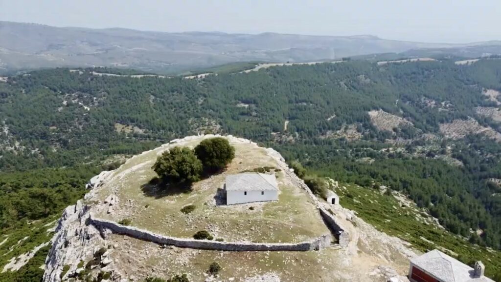Aerial view of an old white house in the village of Kastro on Thassos with the surrounding forests and mountains