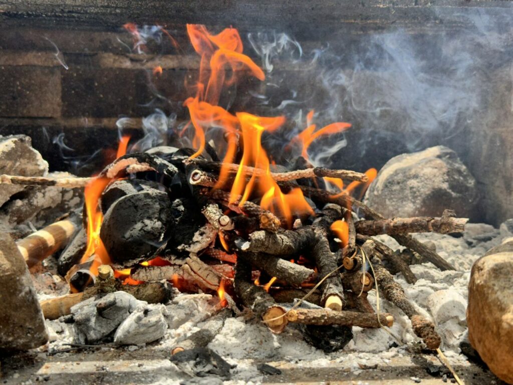 A charcoal and kindling fire in a stone barbecue