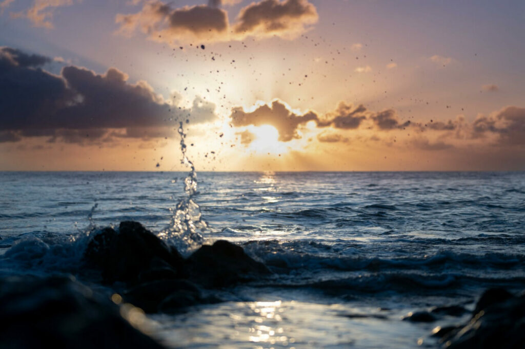 Ocean waves splashing over rocks at sunset